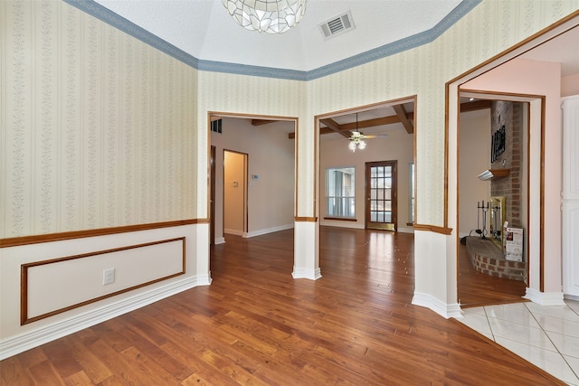 empty room featuring wallpapered walls, baseboards, visible vents, and wood finished floors