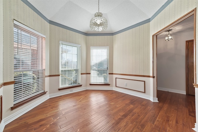 empty room featuring a textured ceiling, baseboards, hardwood / wood-style flooring, and wallpapered walls