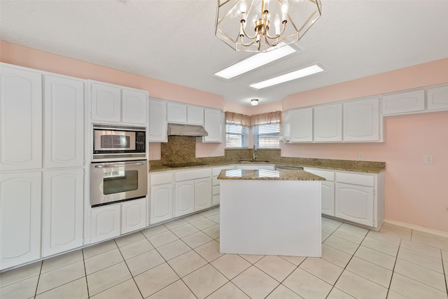 kitchen featuring light tile patterned floors, under cabinet range hood, a sink, white cabinets, and appliances with stainless steel finishes