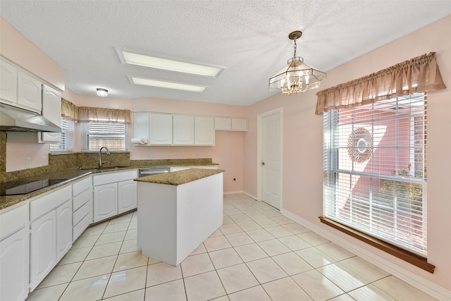 kitchen with black electric stovetop, light tile patterned flooring, a sink, white cabinets, and a center island