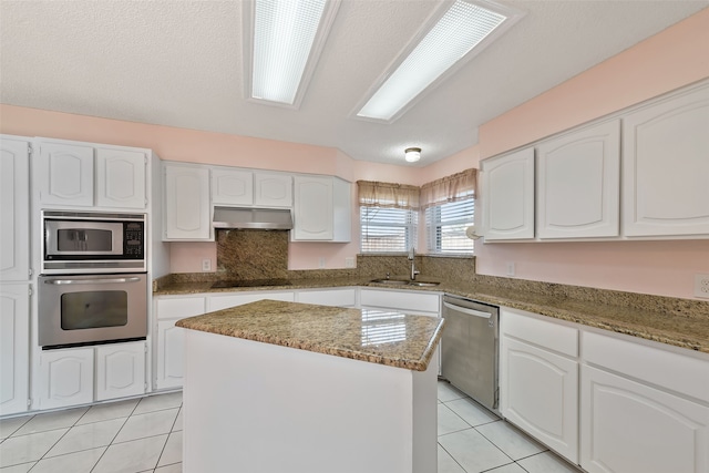 kitchen with stainless steel appliances, light tile patterned flooring, a sink, and under cabinet range hood