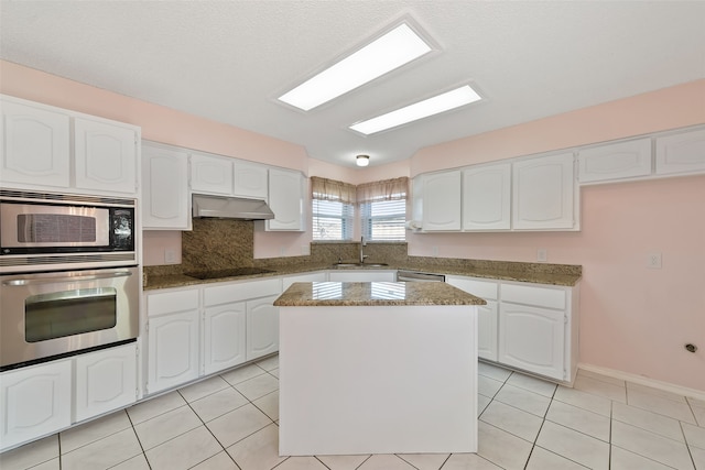 kitchen with appliances with stainless steel finishes, white cabinetry, a sink, and under cabinet range hood