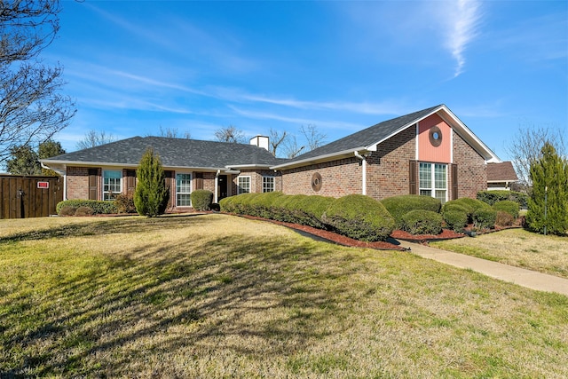 view of front of house featuring brick siding, a front lawn, a chimney, and fence