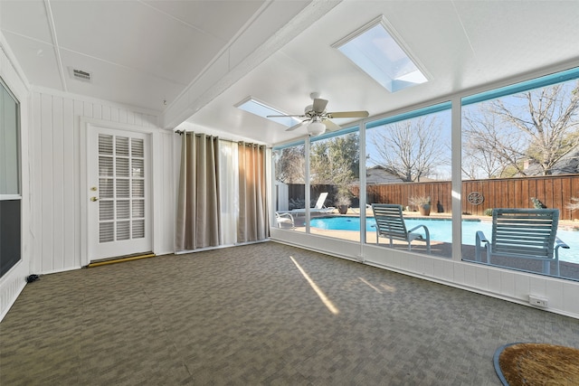 unfurnished sunroom featuring ceiling fan, a skylight, and visible vents