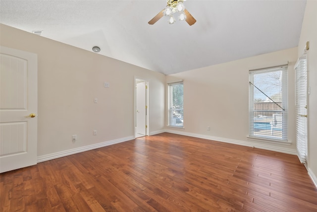 empty room featuring lofted ceiling, baseboards, a wealth of natural light, and wood finished floors