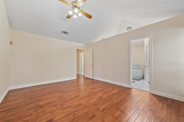 unfurnished room featuring lofted ceiling, ceiling fan, wood finished floors, visible vents, and baseboards