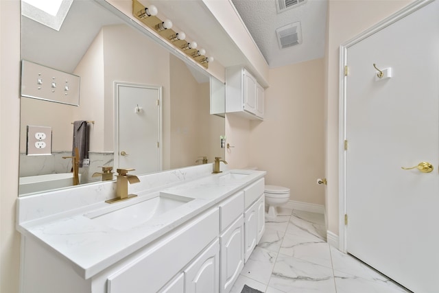 full bath with toilet, marble finish floor, a skylight, and a sink