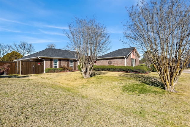 view of front of house with brick siding, a front lawn, and fence