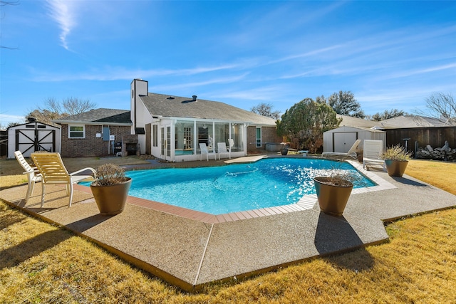 view of swimming pool with an outbuilding, a patio, a lawn, a fenced in pool, and a shed