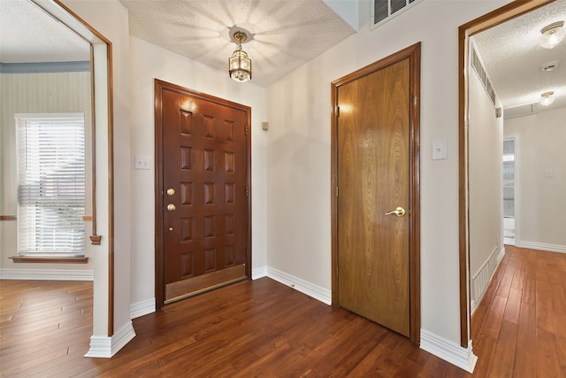 entryway with a textured ceiling, dark wood-style floors, visible vents, and baseboards