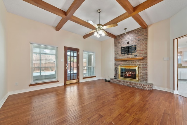 unfurnished living room with a brick fireplace, baseboards, coffered ceiling, and wood finished floors