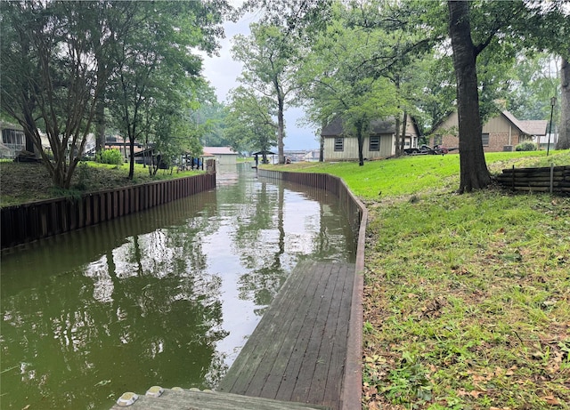 exterior space with a dock, a water view, and a lawn