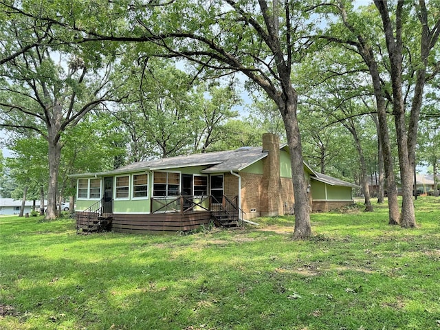 view of front of home with a shingled roof, a sunroom, a chimney, crawl space, and a front yard