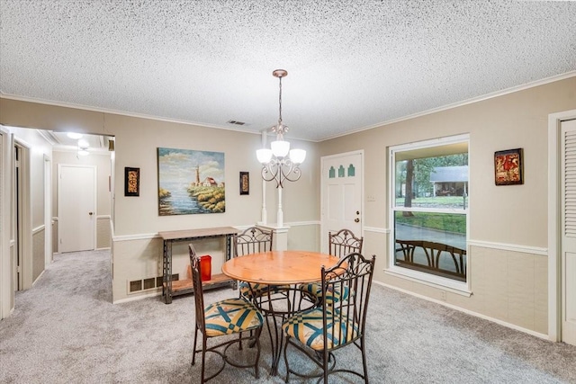 carpeted dining space featuring a notable chandelier, a textured ceiling, visible vents, and crown molding