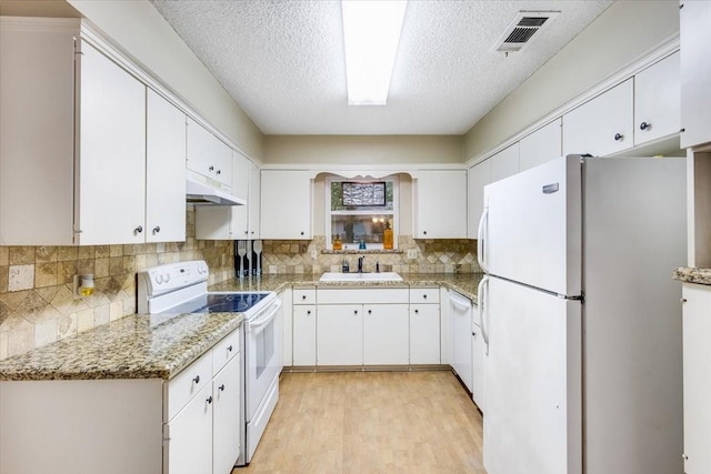 kitchen with under cabinet range hood, white appliances, a sink, visible vents, and light wood-type flooring