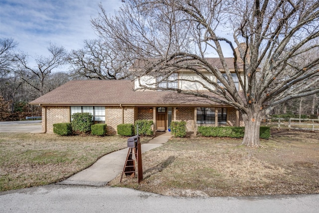 ranch-style house featuring a shingled roof and brick siding