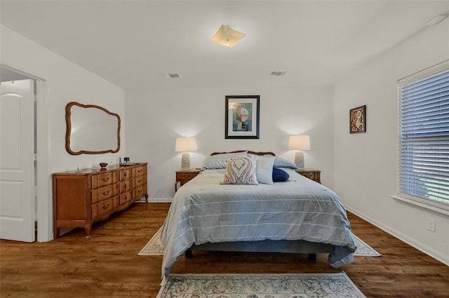 bedroom featuring wood finished floors, visible vents, and baseboards