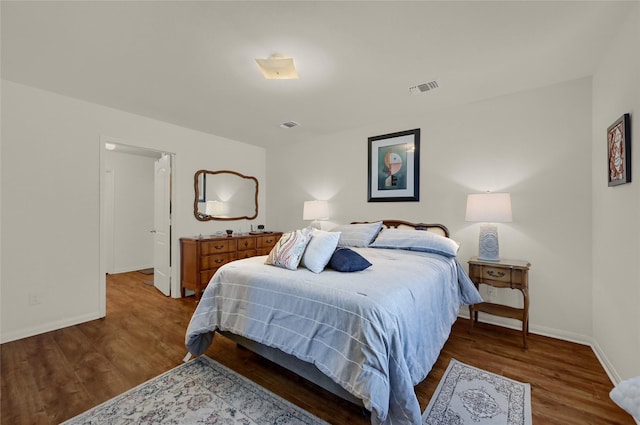 bedroom with baseboards, visible vents, and wood finished floors