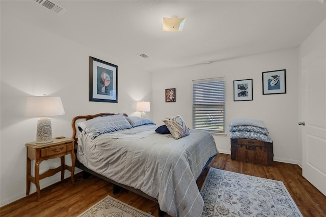 bedroom featuring wood finished floors, visible vents, and baseboards