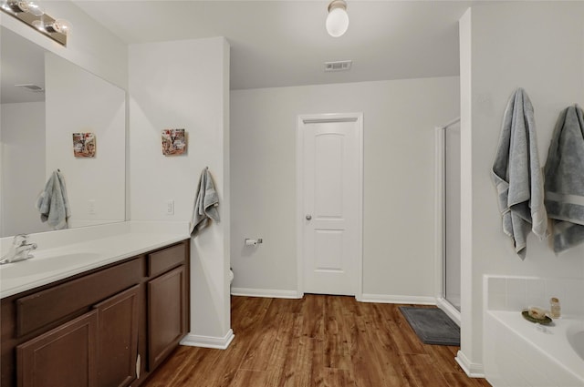 full bath featuring wood finished floors, vanity, visible vents, a shower stall, and a bath