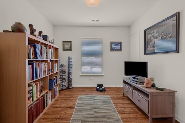 living area with baseboards, visible vents, and wood finished floors