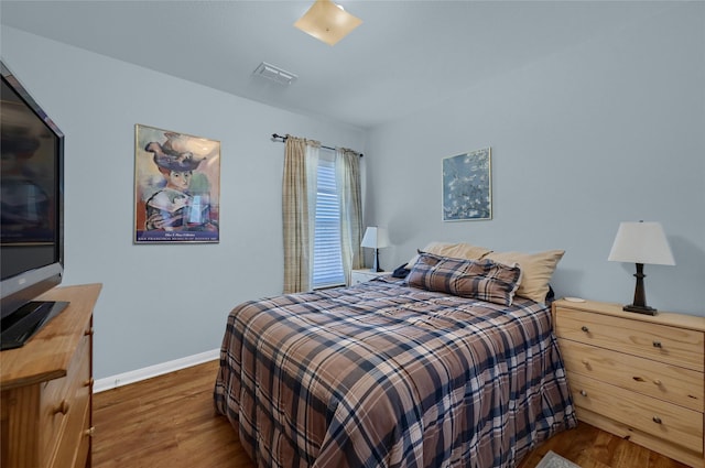 bedroom with visible vents, baseboards, and wood finished floors