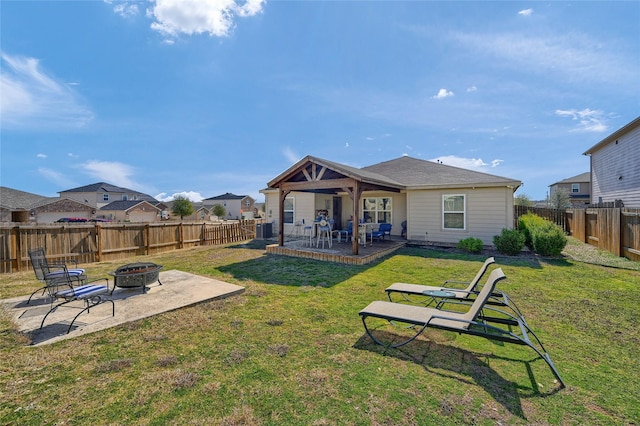 back of property featuring an outdoor fire pit, a lawn, a patio area, and a fenced backyard