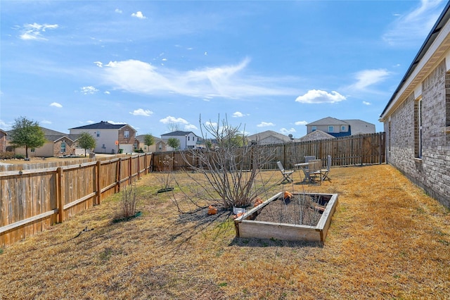 view of yard featuring a garden, a residential view, and a fenced backyard