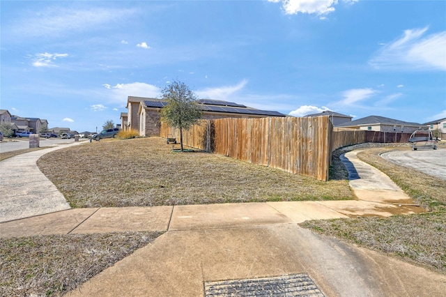 view of side of home featuring solar panels, fence, and a residential view