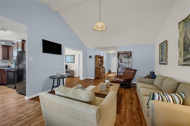 living room with light wood-style flooring, high vaulted ceiling, and baseboards