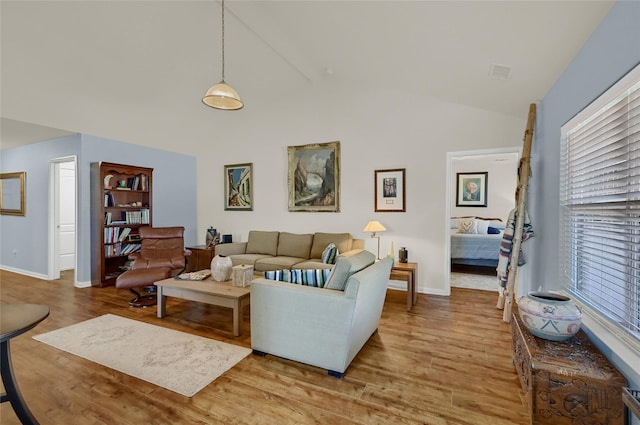 living room featuring high vaulted ceiling, wood finished floors, and baseboards