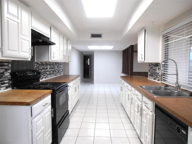 kitchen featuring light tile patterned floors, under cabinet range hood, a sink, visible vents, and black appliances