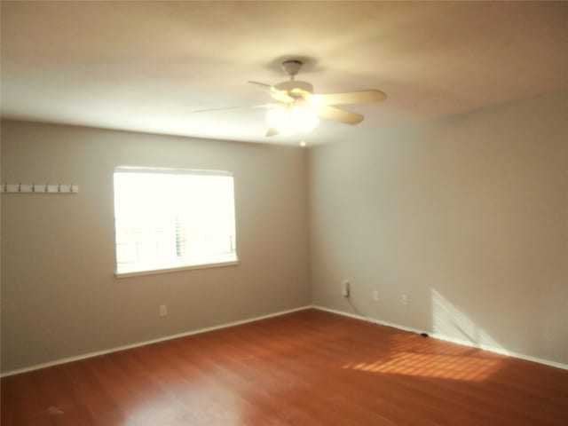 spare room featuring wood finished floors, a ceiling fan, and baseboards