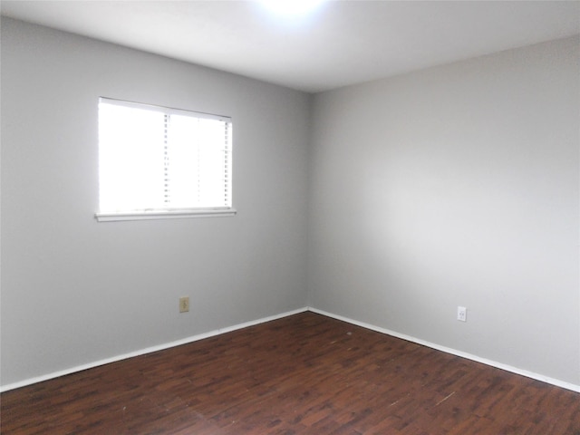 empty room featuring dark wood-style floors and baseboards