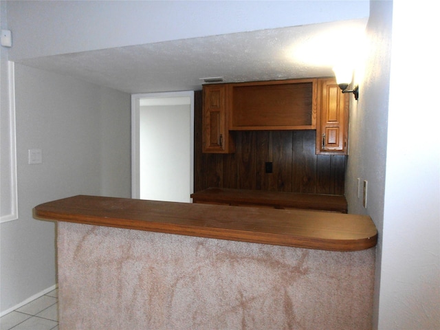 kitchen featuring baseboards, light tile patterned flooring, visible vents, and brown cabinets