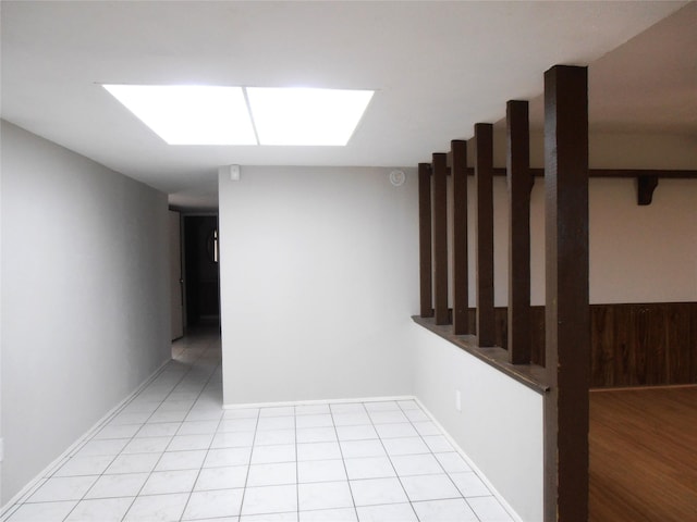 unfurnished room with a skylight, wooden walls, and light tile patterned floors