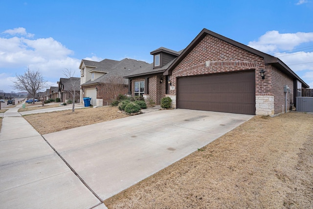 view of front facade with central air condition unit, a garage, brick siding, driveway, and a residential view