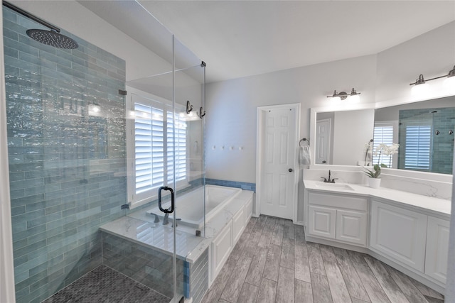 bathroom with a stall shower, a garden tub, wood finished floors, and vanity