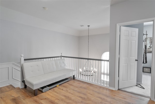 living area featuring a chandelier, a wainscoted wall, wood finished floors, and a decorative wall