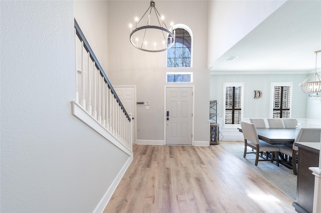 entrance foyer featuring visible vents, stairway, an inviting chandelier, light wood-style floors, and baseboards