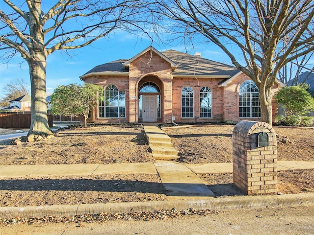 view of front of house with brick siding and roof with shingles