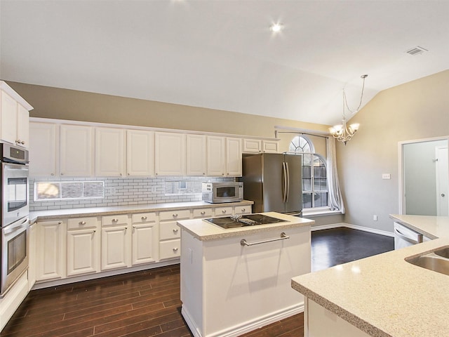 kitchen with lofted ceiling, stainless steel appliances, a kitchen island, light countertops, and dark wood finished floors