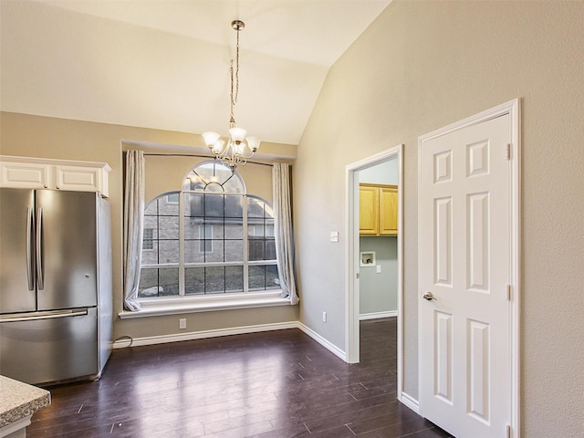 unfurnished dining area featuring lofted ceiling, dark wood-style flooring, a notable chandelier, and baseboards