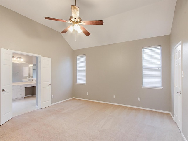 unfurnished bedroom featuring ensuite bath, baseboards, vaulted ceiling, and light colored carpet