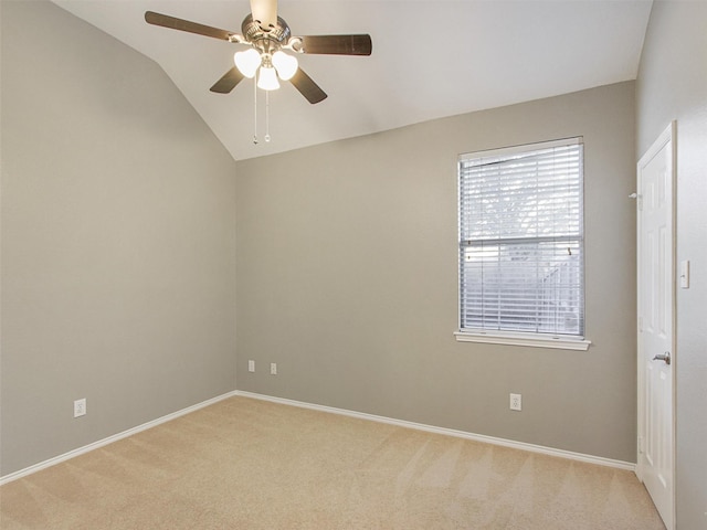 spare room featuring light carpet, baseboards, vaulted ceiling, and a ceiling fan