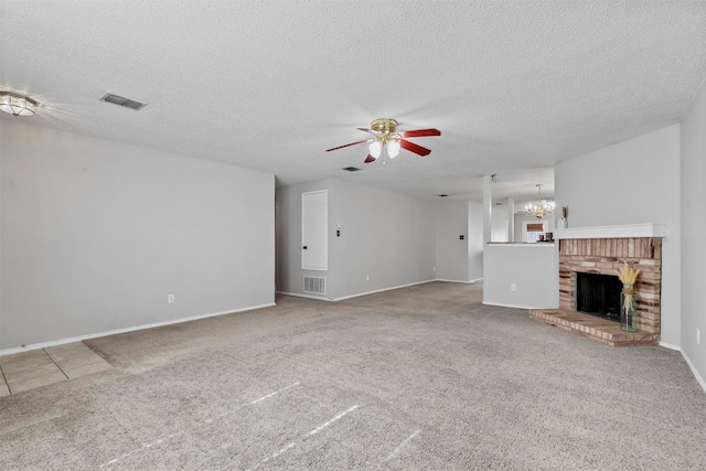 unfurnished living room featuring a brick fireplace, carpet, visible vents, and ceiling fan with notable chandelier