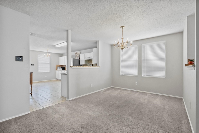 spare room with light carpet, light tile patterned floors, a textured ceiling, and a notable chandelier