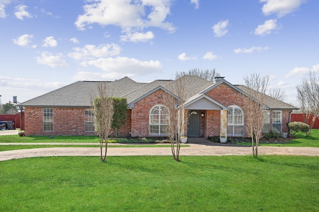 single story home with fence, a shingled roof, curved driveway, a front lawn, and brick siding