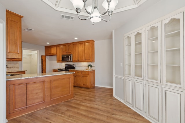 kitchen featuring visible vents, tasteful backsplash, stainless steel appliances, an inviting chandelier, and light stone countertops