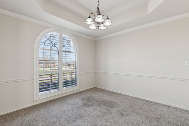 carpeted empty room with an inviting chandelier, a raised ceiling, baseboards, and ornamental molding